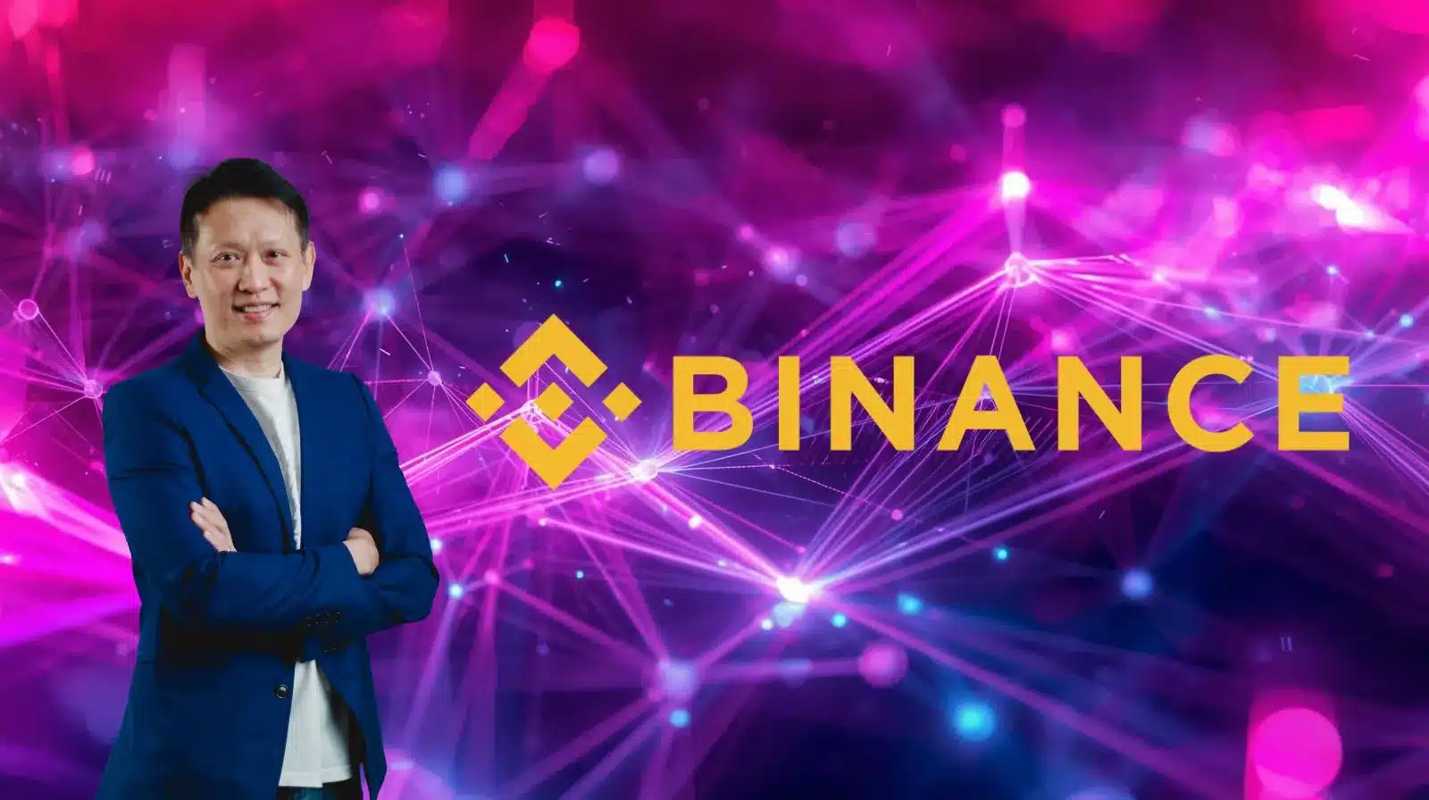 Mavi blazer giymiş bir adam, kolları çapraz şekilde, canlı pembe ve mor tonlarda dijital bir ağ arka planının önünde duruyor. Sağ tarafında sarı Binance logosu ve “BINANCE” yazısı belirgin şekilde yer alıyor; görsel kripto para veya blokzincir temasını yansıtıyor.